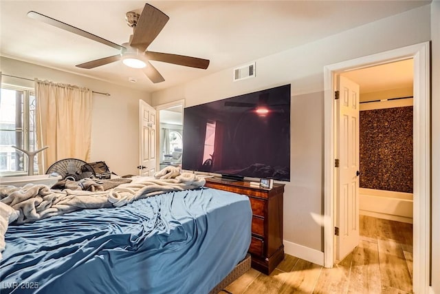 bedroom featuring baseboards, wood finished floors, visible vents, and ceiling fan