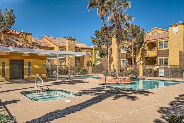 community pool with a patio, a community hot tub, and fence