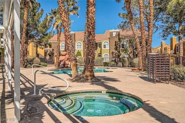 community pool featuring a residential view, fence, a community hot tub, and a patio area