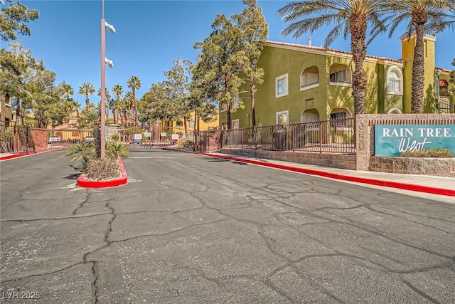 view of street featuring curbs, street lighting, sidewalks, and a gated entry