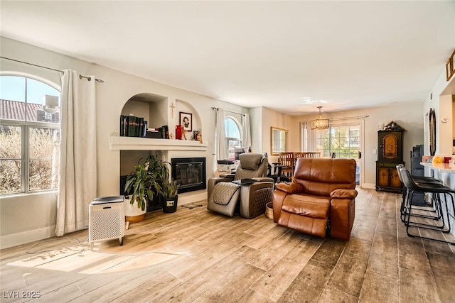 living room featuring baseboards, wood finished floors, and a glass covered fireplace