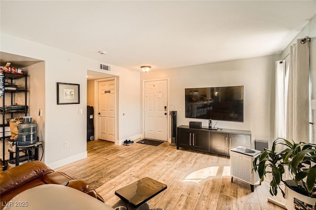 living room with visible vents, baseboards, and light wood finished floors