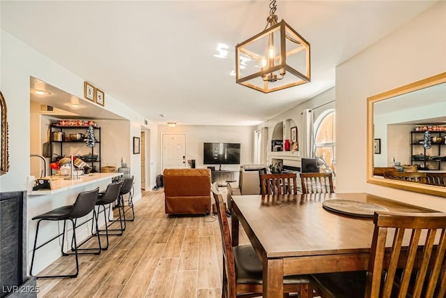 dining area with arched walkways, an inviting chandelier, and light wood finished floors