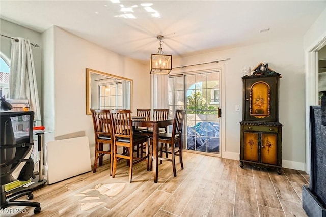 dining room with wood finished floors, a notable chandelier, a healthy amount of sunlight, and baseboards