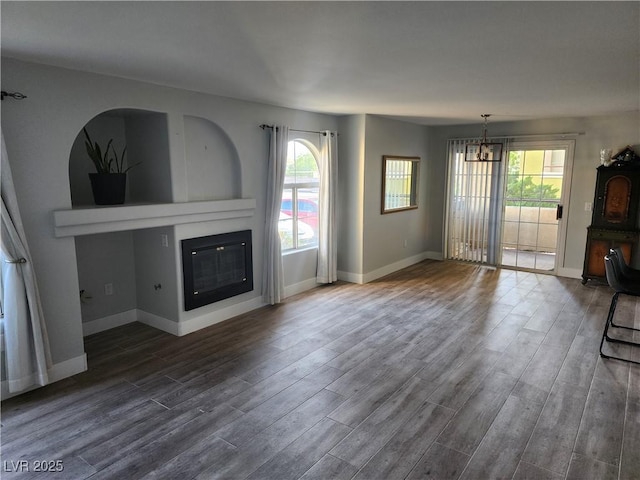 7950 W Flamingo Rd Unit 1081, Las Vegas, NV 89147 - unfurnished living room featuring a chandelier, dark wood-style floors, and healthy amount of natural light