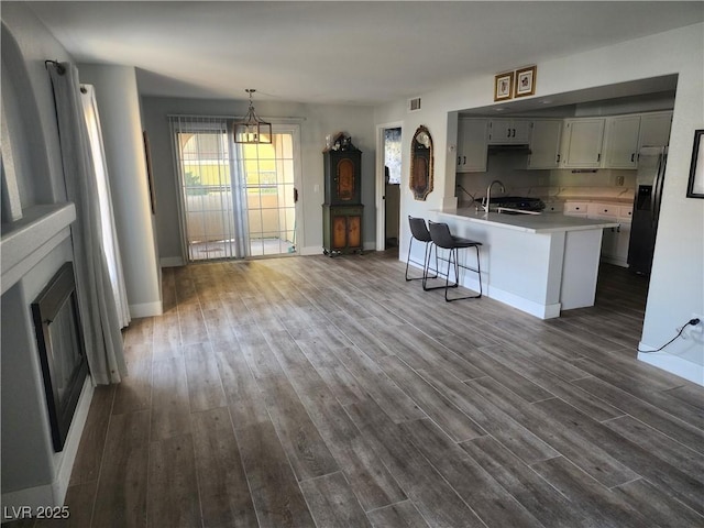 7950 W Flamingo Rd Unit 1081, Las Vegas, NV 89147 - kitchen with stainless steel fridge with ice dispenser, a peninsula, light countertops, dark wood-style floors, and a chandelier