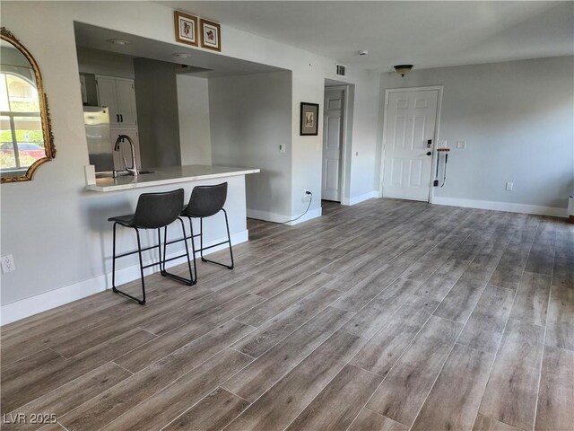 7950 W Flamingo Rd Unit 1081, Las Vegas, NV 89147 - kitchen with refrigerator, wood finished floors, a kitchen bar, and light countertops
