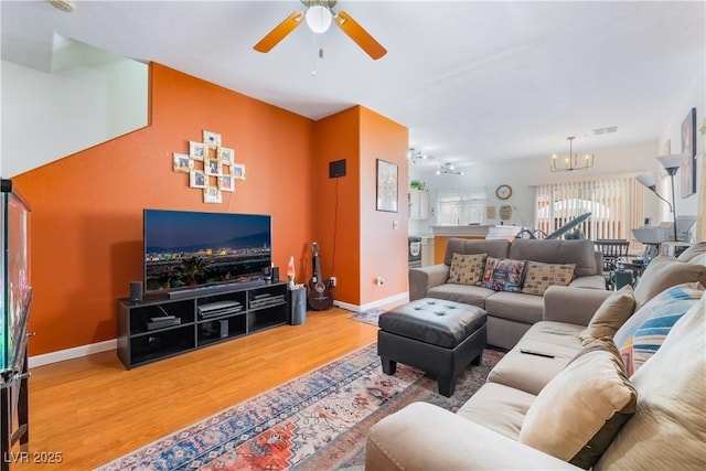 living room with hardwood / wood-style flooring and ceiling fan with notable chandelier