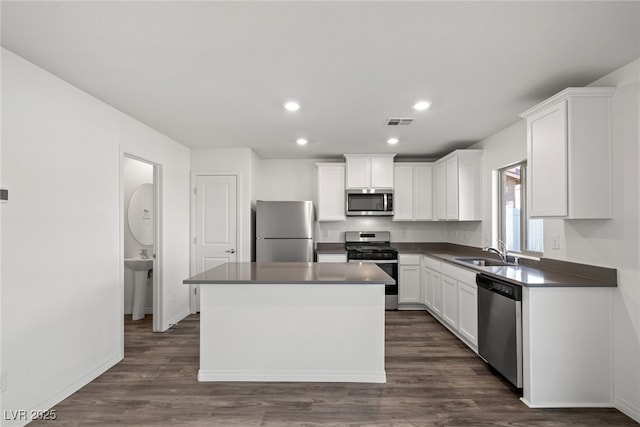 kitchen featuring sink, dark hardwood / wood-style flooring, a kitchen island, stainless steel appliances, and white cabinets