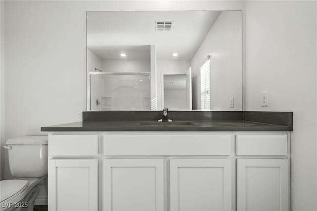 bathroom with vanity, toilet, and a shower with door