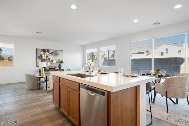 kitchen featuring light hardwood / wood-style floors, stainless steel dishwasher, a kitchen island with sink, and sink