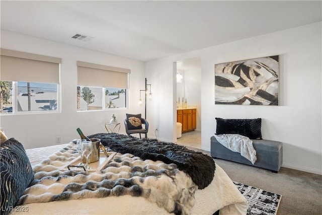 bedroom featuring connected bathroom and light colored carpet