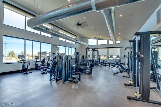 gym featuring a towering ceiling and ceiling fan