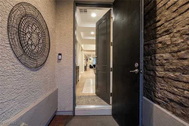 hallway with a tray ceiling and crown molding