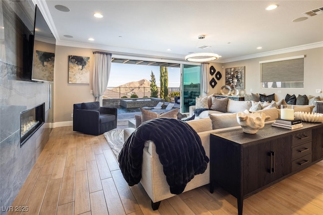 living room featuring crown molding, light wood-type flooring, and a high end fireplace