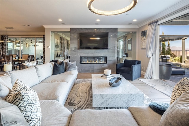 living room with a tile fireplace, ornamental molding, and light hardwood / wood-style floors