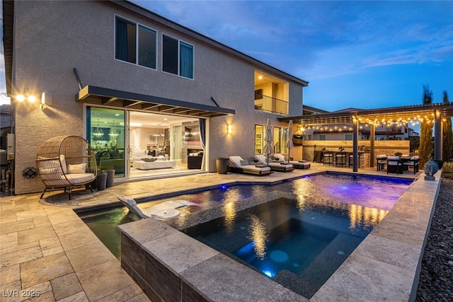 pool at dusk with exterior bar, a pergola, a patio, and an in ground hot tub