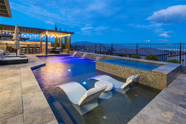 pool at dusk with a jacuzzi, an outdoor bar, a patio, and a mountain view