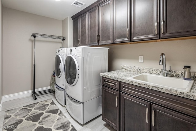 laundry area with cabinets, washer and dryer, and sink