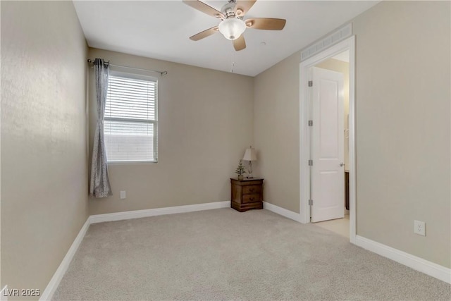 empty room featuring ceiling fan and light colored carpet