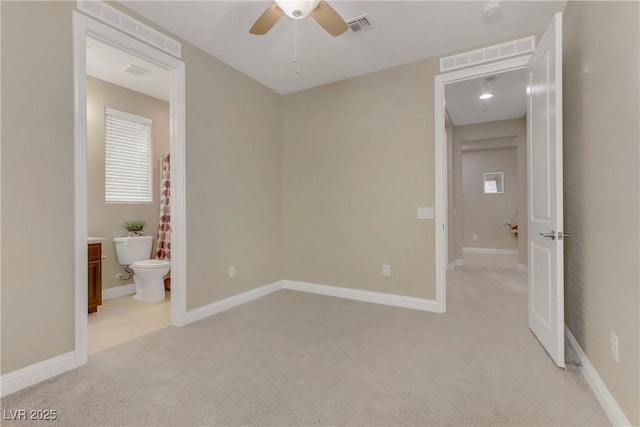 unfurnished bedroom featuring ceiling fan, ensuite bath, and light carpet