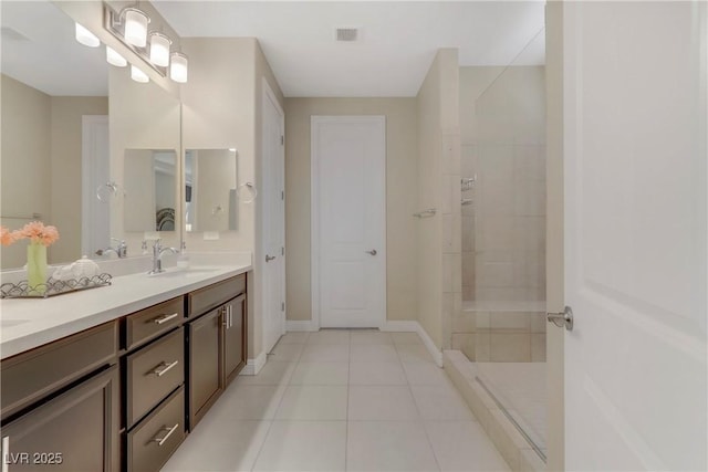 bathroom with tile patterned flooring, vanity, and a tile shower