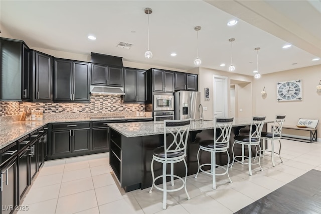 kitchen with hanging light fixtures, appliances with stainless steel finishes, and a kitchen island with sink