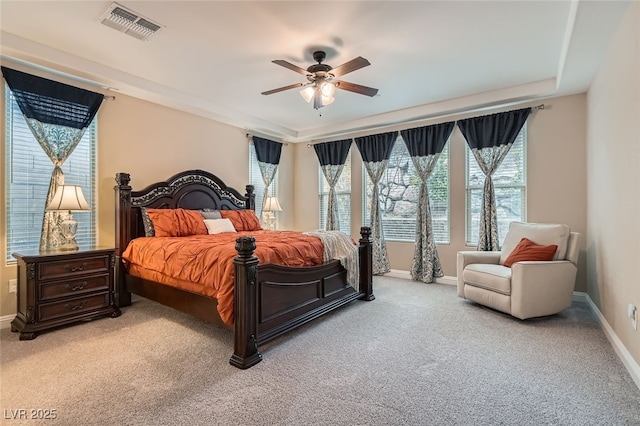 carpeted bedroom featuring ceiling fan and a tray ceiling