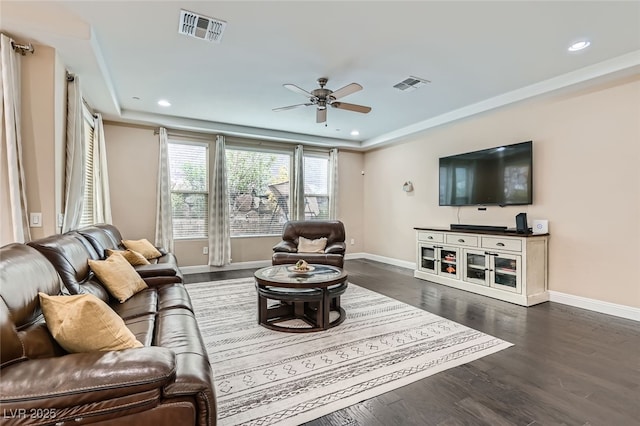 living room with ceiling fan, dark hardwood / wood-style flooring, and a tray ceiling