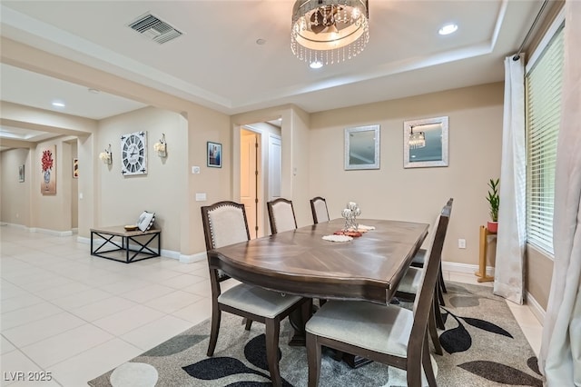 tiled dining room with a raised ceiling