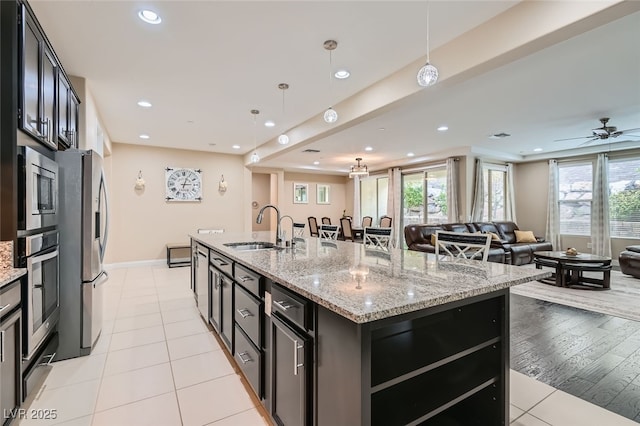 kitchen with pendant lighting, appliances with stainless steel finishes, an island with sink, and sink