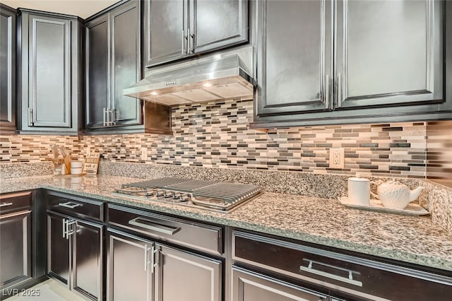 kitchen featuring stainless steel gas stovetop, light stone countertops, and decorative backsplash