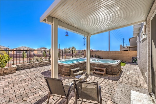 view of patio / terrace featuring a swimming pool, a fenced backyard, and a hot tub