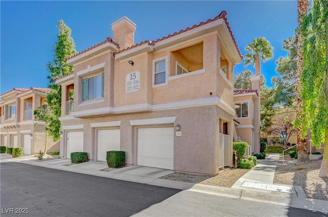 view of front of house featuring a garage, a tile roof, and stucco siding