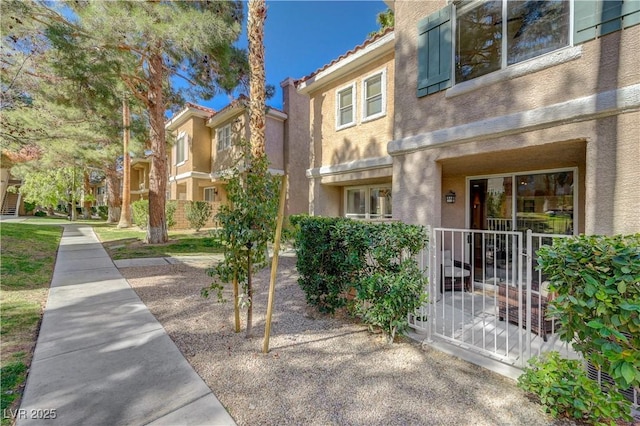 exterior space with fence, a tile roof, a gate, and stucco siding