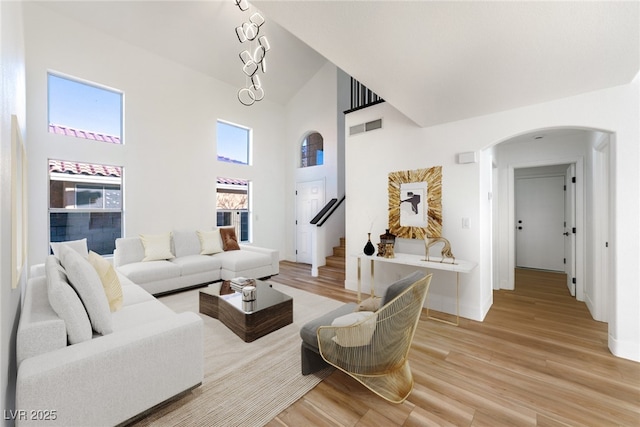 living room featuring a towering ceiling and light hardwood / wood-style flooring