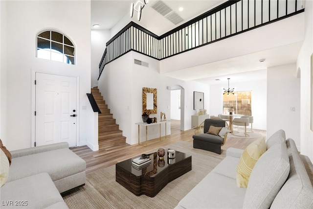 living room with an inviting chandelier, a towering ceiling, and light hardwood / wood-style floors