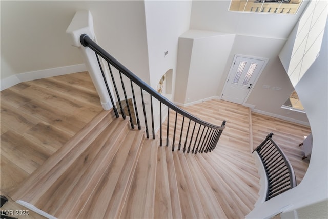 stairway featuring wood-type flooring and a high ceiling