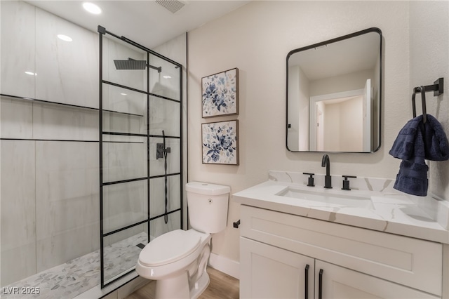 bathroom with tiled shower, vanity, toilet, and hardwood / wood-style floors