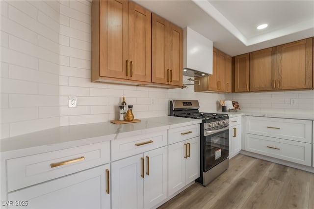 kitchen with gas range, light wood-type flooring, decorative backsplash, and white cabinets