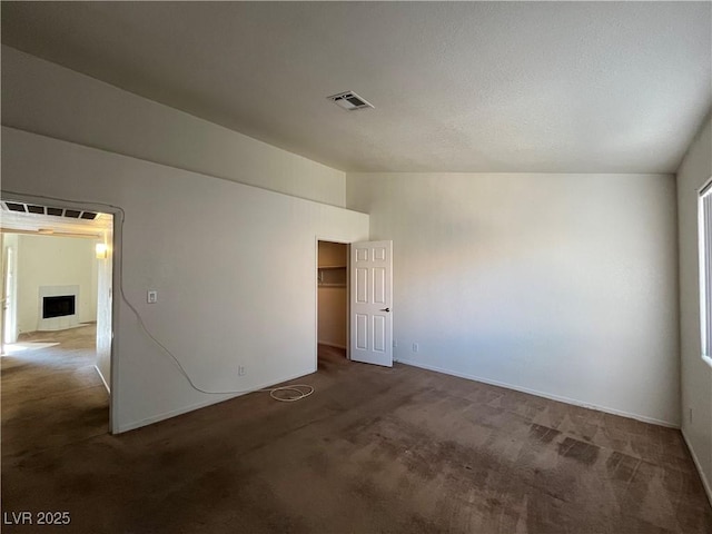 unfurnished room featuring dark carpet and vaulted ceiling