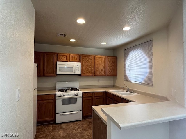 kitchen featuring white appliances, kitchen peninsula, sink, and a textured ceiling