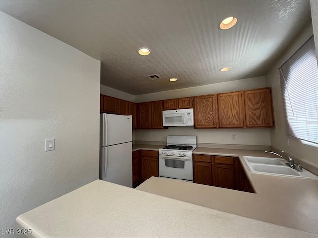 kitchen featuring white appliances, kitchen peninsula, sink, and a textured ceiling