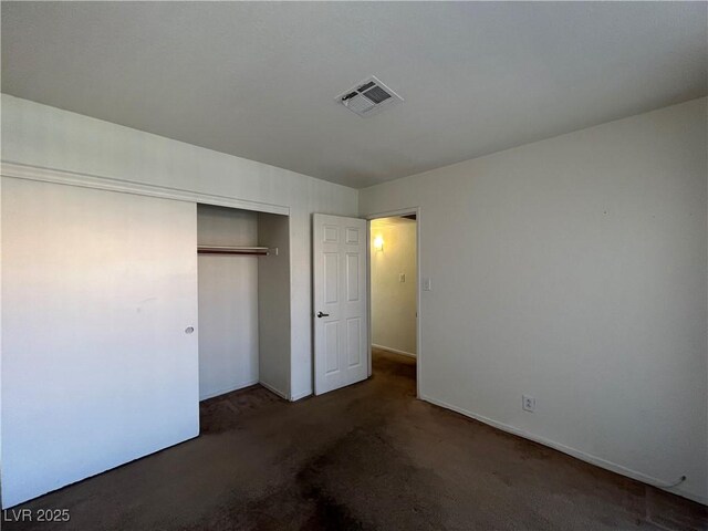 unfurnished bedroom with dark carpet and a closet