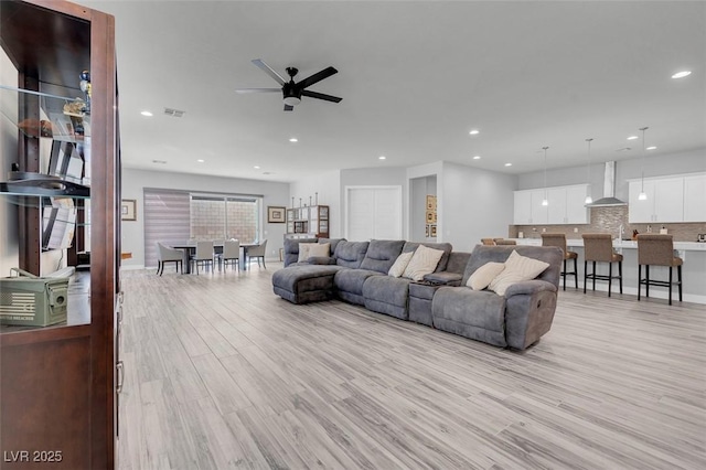 living room featuring ceiling fan, sink, and light wood-type flooring