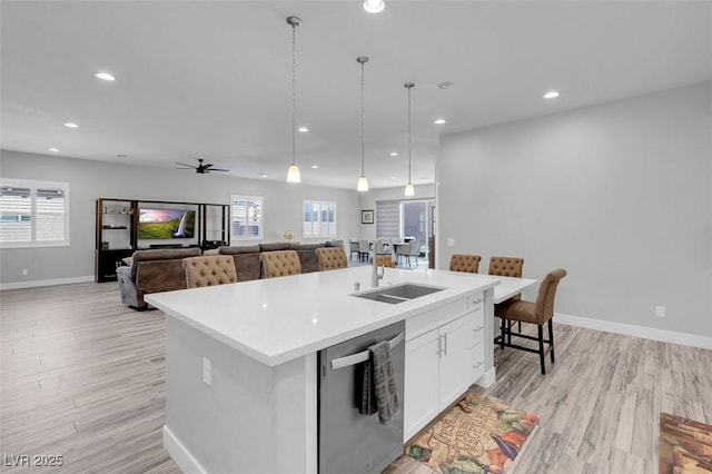 kitchen with pendant lighting, white cabinetry, an island with sink, sink, and stainless steel dishwasher