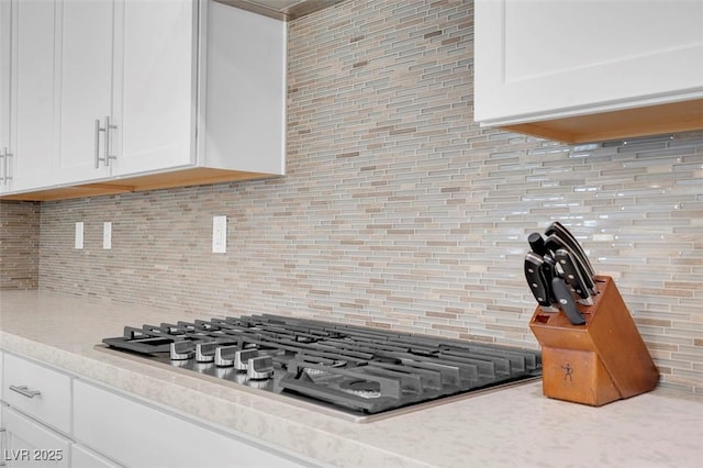 kitchen with white cabinetry, light stone countertops, stainless steel gas cooktop, and decorative backsplash