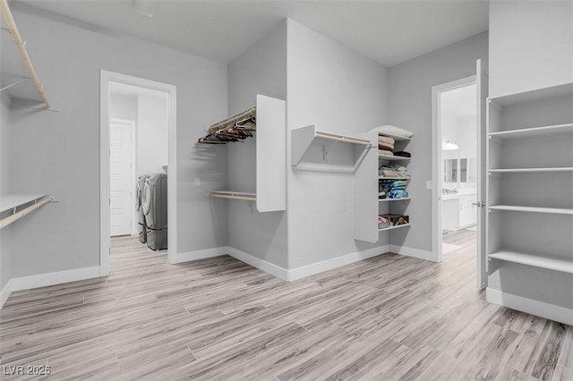 walk in closet with washing machine and dryer and light hardwood / wood-style floors