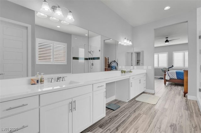 bathroom featuring ceiling fan, vanity, a shower with shower door, and wood-type flooring