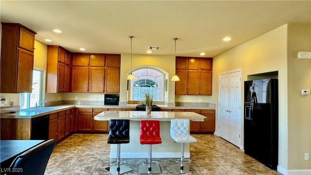 kitchen with a kitchen island, pendant lighting, sink, a breakfast bar area, and black appliances